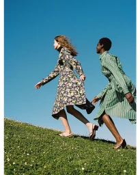 Two female models walking up a grassy hill against a clear blue sky, captured in Paris by Wai Lin Tse.