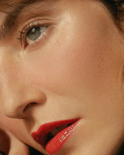 Close-up portrait of a fair-skinned young adult female with red lipstick, visible eye, and an overall beauty and fashion focus.