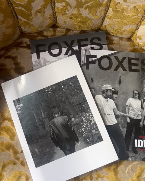Close-up shot of three Foxes magazine covers stacked on a textured yellow patterned sofa. Black and white photography featured.