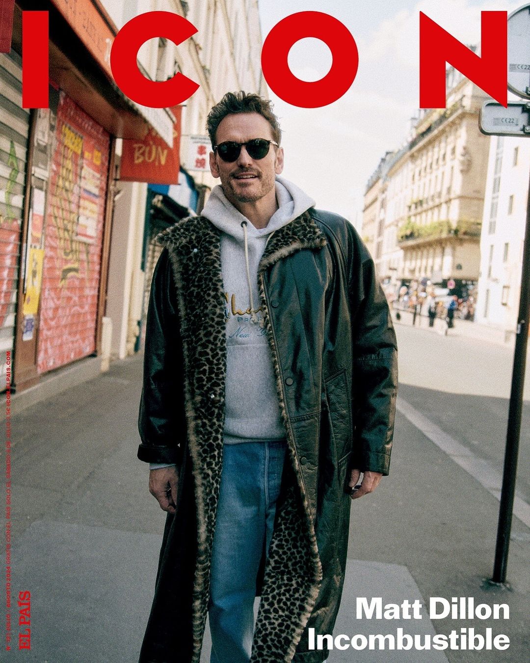 Matt Dillon cover photo for Icon magazine featuring the actor outdoors in a printed coat, hoodie, and jeans, with a Paris street background.