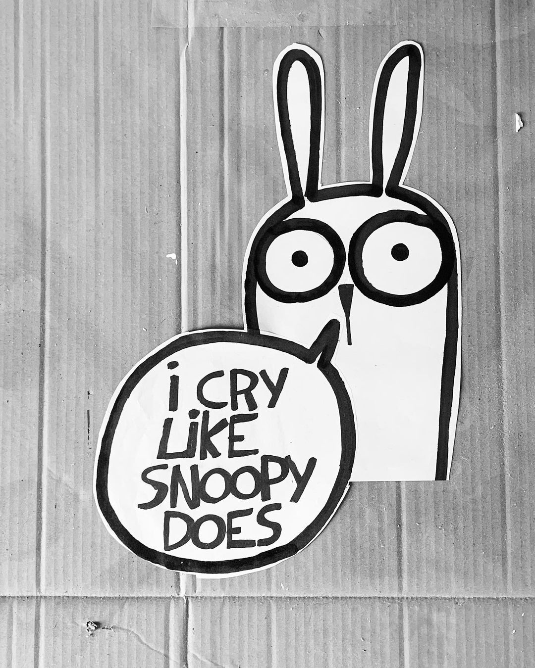 Illustration of cartoon rabbit with speech bubble saying, "I cry like Snoopy does" on corrugated cardboard, black and white.