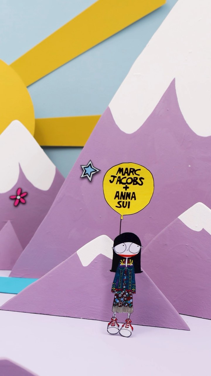 Stylized paper art scene features an animated character holding a balloon against a backdrop of mountains, sky, and sun.