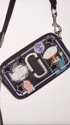 Black leather crossbody bag with illustrative character graphics and star appliques by illustrator Will Broome.