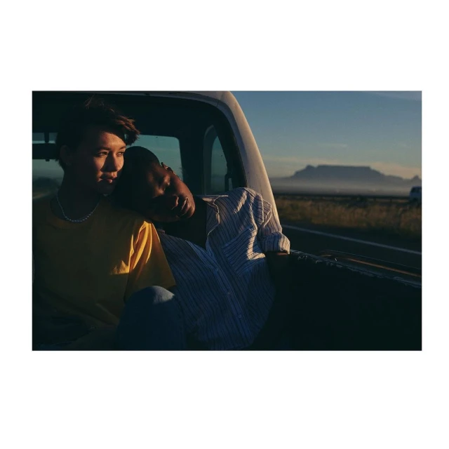 Two people in the bed of a pickup truck, with a mountain range in the background, creating a serene and intimate travel portrait.