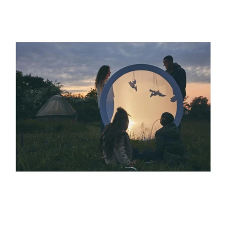 Family gathers in a grassy field at dusk, enjoying an illuminated, transparent sphere with bird silhouettes.  A yurt is visible.