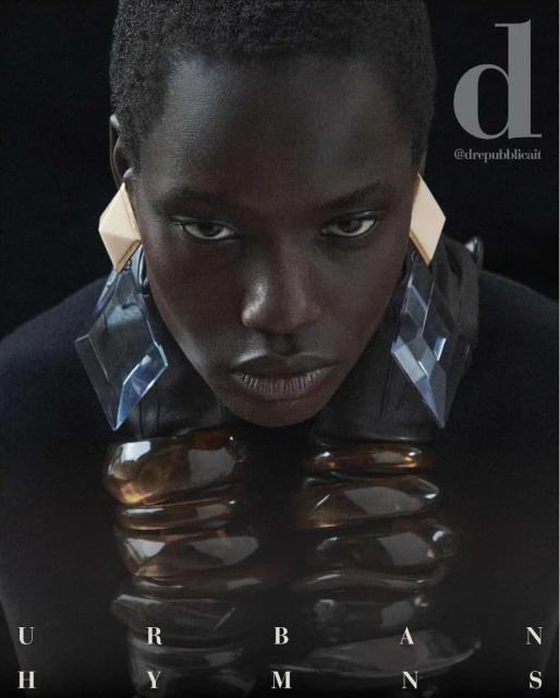 Close-up fashion shot of a dark-skinned model with geometric earrings and a collar necklace, set against a dark background. 