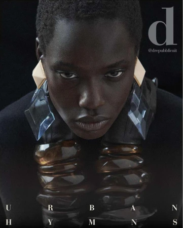 Close-up fashion shot of a dark-skinned model with geometric earrings and a collar necklace, set against a dark background. 