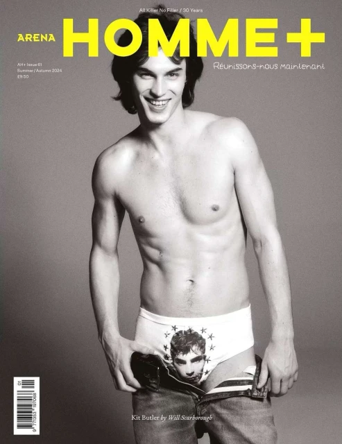 Black-and-white magazine cover featuring a topless adult male model in briefs and jeans, smiling at the camera against a grey backdrop.