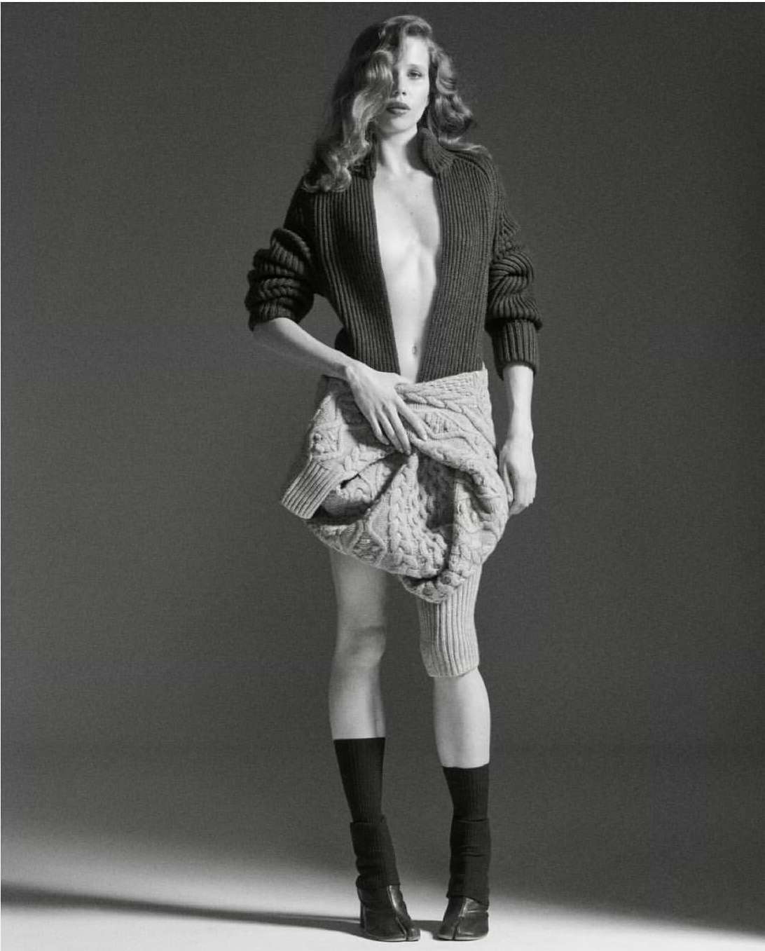 Monochrome fashion portrait by Will Scarborough of a woman in a dark knitted cardigan and twisted cable sweater tied around her waist.