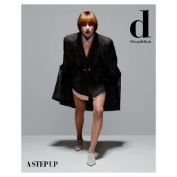 Model with bob haircut wearing an oversized plaid blazer and white heeled mules in a studio setting.