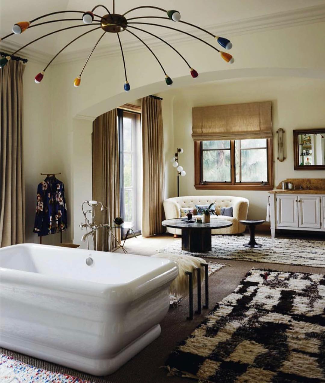 Bright and spacious bathroom with modern bathtub, colorful pendant light fixture, and light-colored walls and carpets create a relaxing atmosphere.