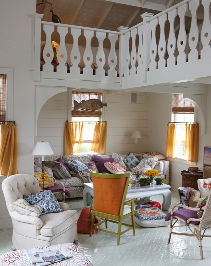 Living room interior with white walls, patterned sofa, and decorative fish hanging near a window with brown curtains. Balcony above.