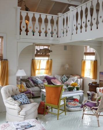 Living room interior with white walls, patterned sofa, and decorative fish hanging near a window with brown curtains. Balcony above.