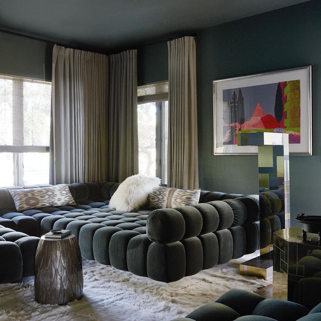 Interior of living room showcases a unique modern modular couch, patterned pillows, throw blanket, side table, and art.