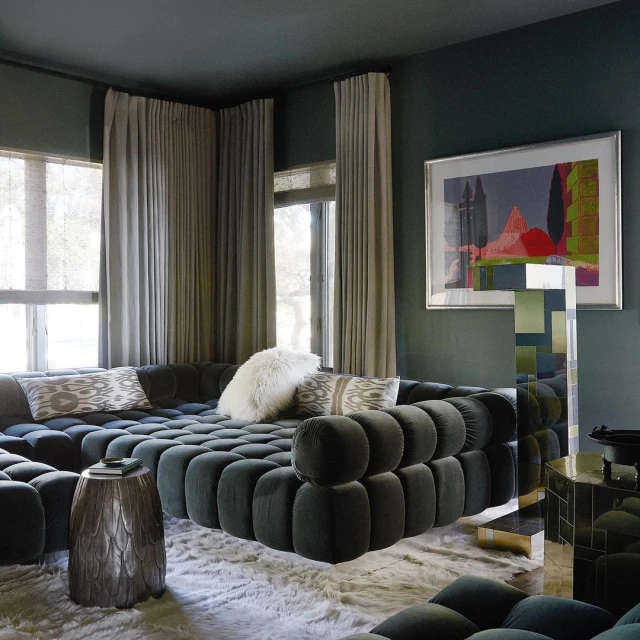 Interior of living room showcases a unique modern modular couch, patterned pillows, throw blanket, side table, and art. 