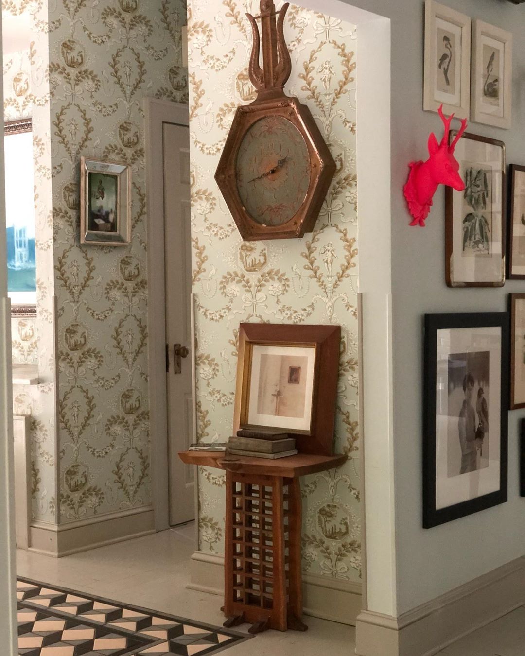 Hallway interior featuring antique wall clock, framed art, and ornate wallpaper, creating a vintage and decorative home aesthetic.