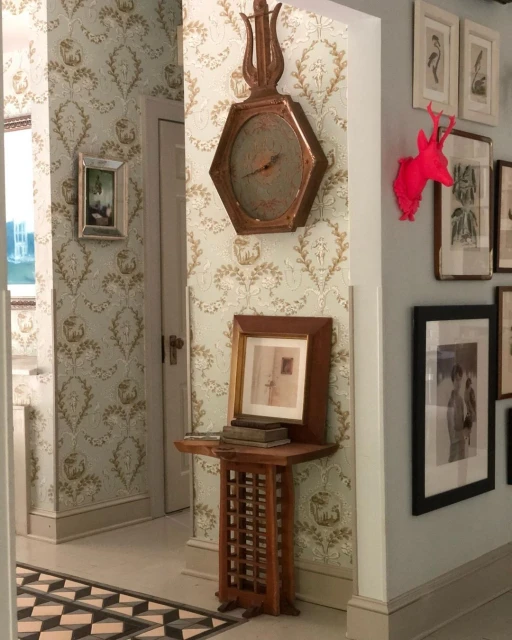 Hallway interior featuring antique wall clock, framed art, and ornate wallpaper, creating a vintage and decorative home aesthetic.