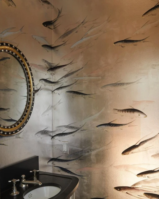 Bathroom interior featuring a black vanity with a white sink, a round mirror, and wallpaper with a fish pattern in black and silver.