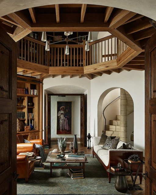 Interior view of a living room with two armchairs, a daybed, a coffee table, and a bookcase in a home with architectural design.
