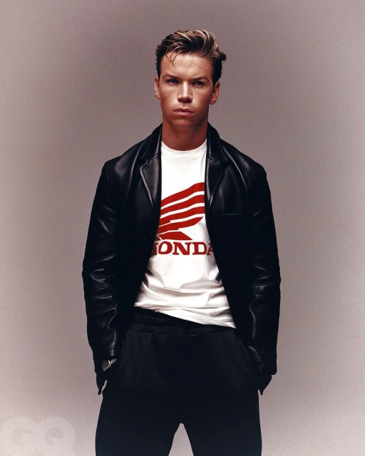 Adult male posing in black leather jacket over a white t-shirt with the Honda logo, against a light grey background, GQ logo at the bottom.