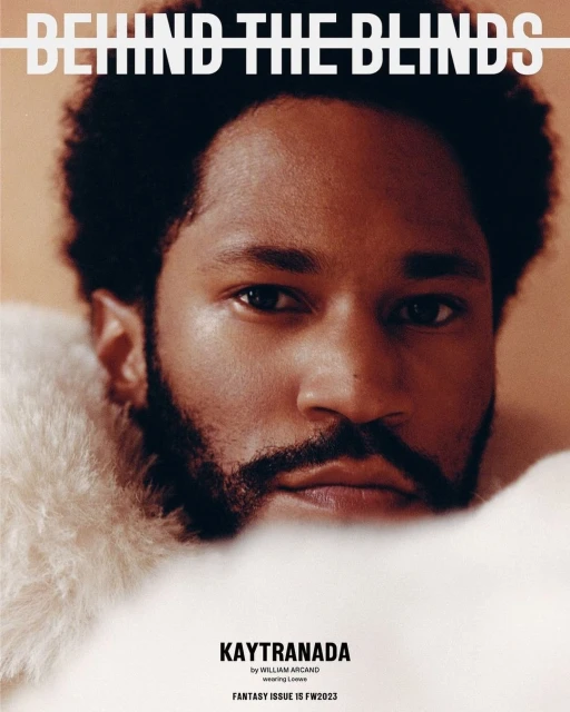 Close-up studio shot of adult male with a beard, framed by fluffy white material, featured on the cover of 'Behind The Blinds'.