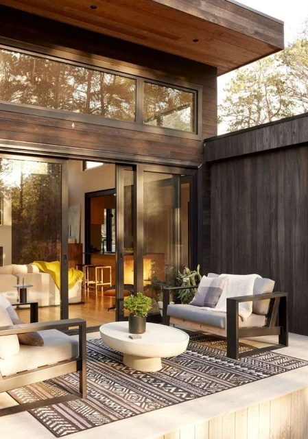 Outdoor patio with modern chairs and concrete coffee table, showcasing contemporary home design and backyard living space.