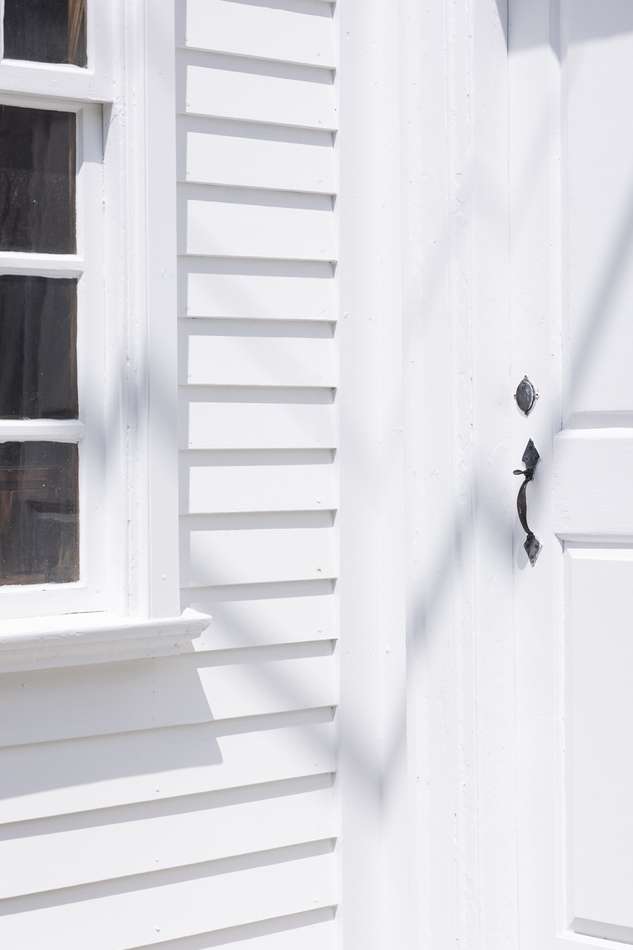 Architectural detail showcases a white window and a door with a handle, emphasizing clean lines and bright, minimalist aesthetic.