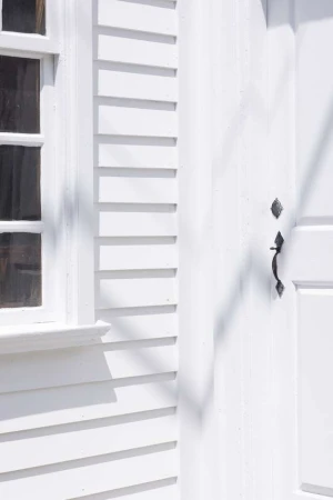 Architectural detail showcases a white window and a door with a handle, emphasizing clean lines and bright, minimalist aesthetic.