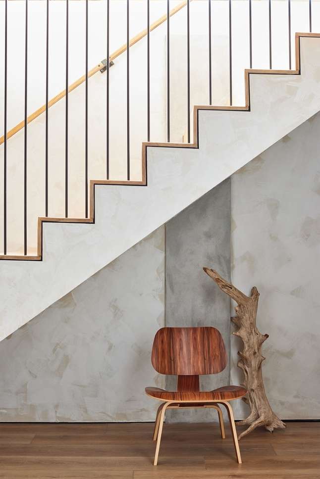 Stairway with wooden steps, black metal railing, and a wood chair with a unique branch for interior design and home architecture.