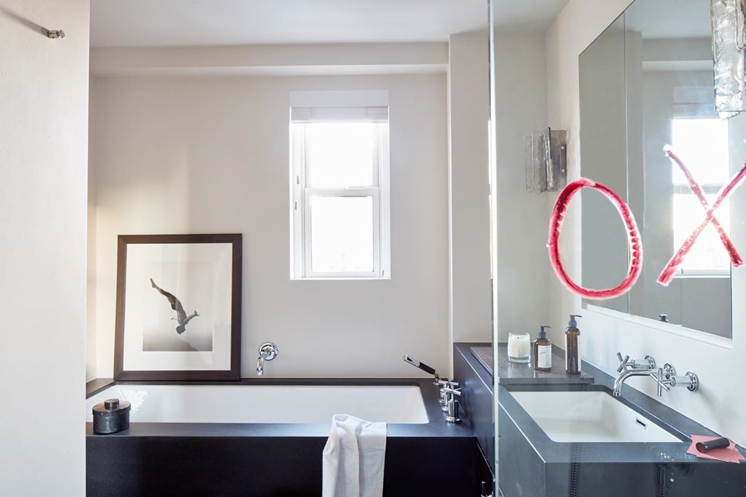 Interior shot of a modern bathroom with a black and white photograph of a diver, minimalist decor, a white bathtub and a sink.