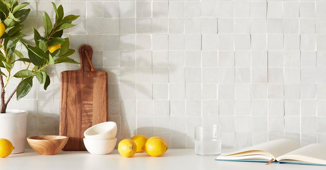 Still life featuring lemons, open book, and cutting board against a tiled backdrop creates a serene and inviting scene indoors.