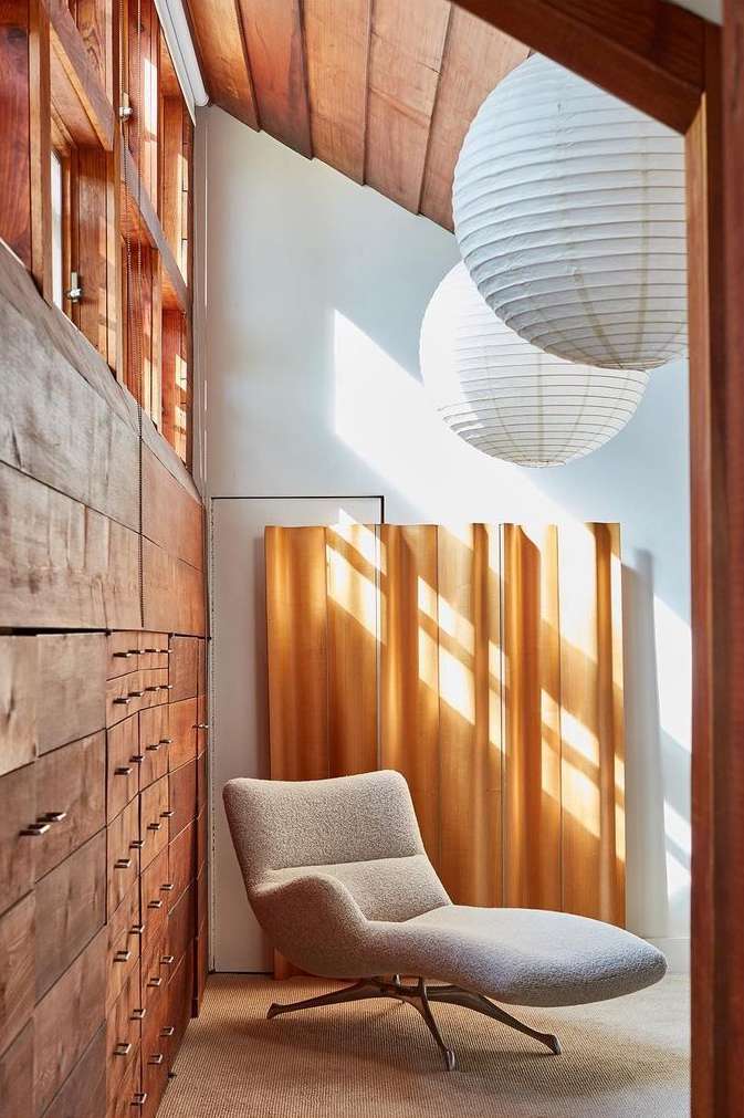 Interior view of an architecturally designed home featuring a chaise lounge, wooden storage, and paper lanterns for soft, ambient lighting.