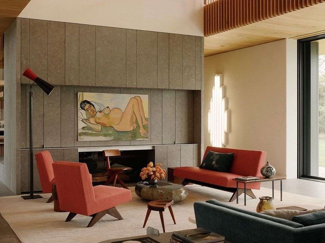 Modern living room interior with stone fireplace wall featuring an art painting above, comfortable seating, and natural light through the window.