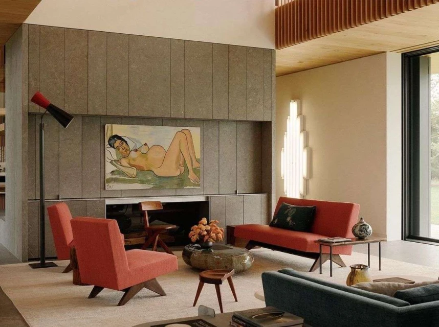 Modern living room interior with stone fireplace wall featuring an art painting above, comfortable seating, and natural light through the window.