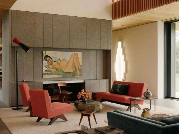 Modern living room interior with stone fireplace wall featuring an art painting above, comfortable seating, and natural light through the window.