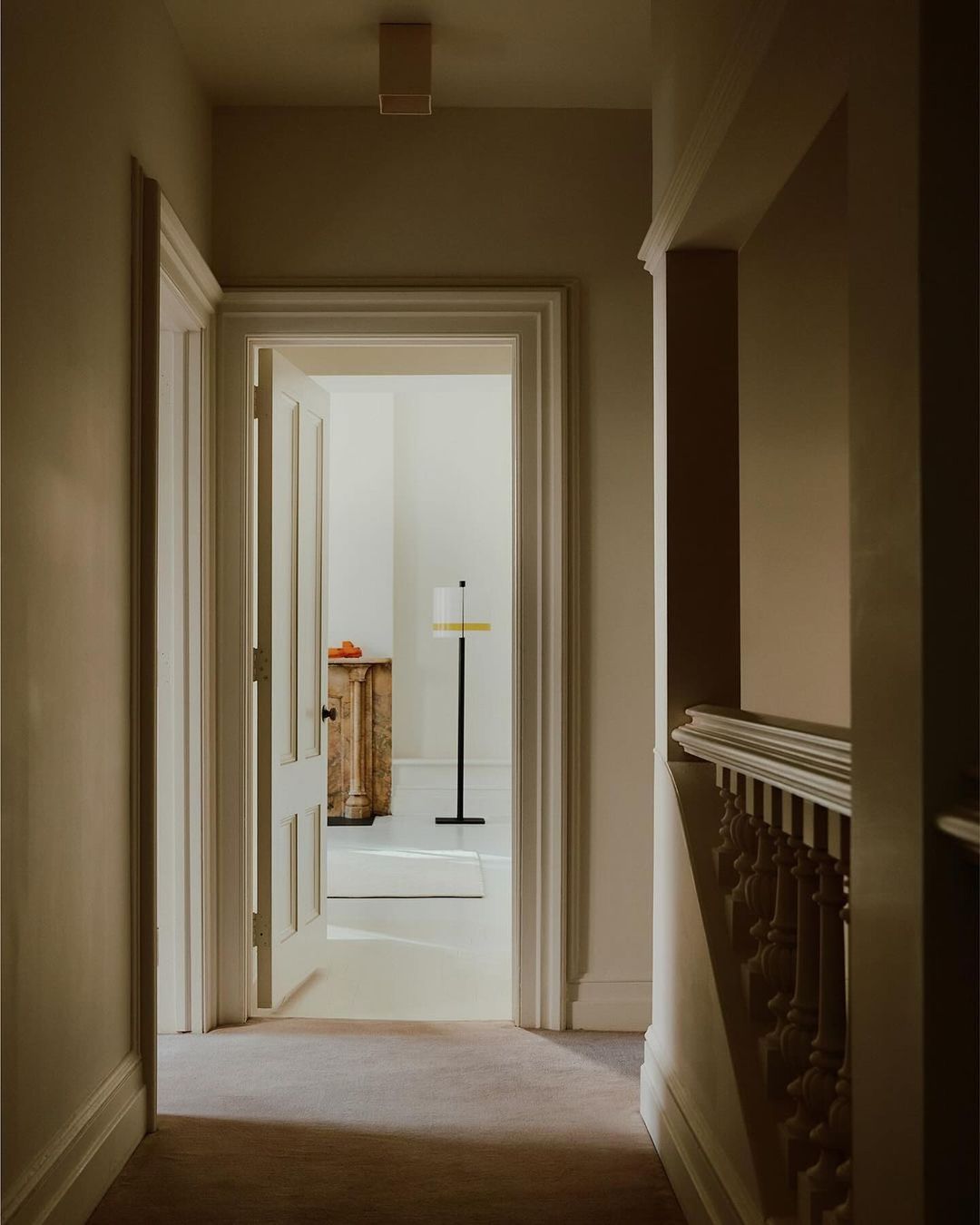 Interior view of a hallway leading to a room with antique cabinet and lamp; neutral color palette; Interior design and architecture.