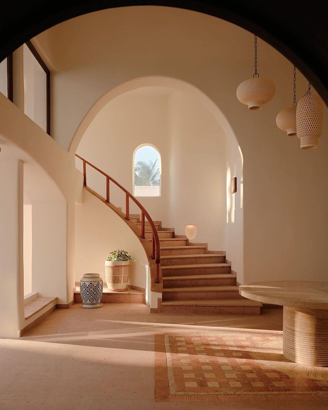 Interior view of a modern home featuring a staircase, arched doorways, and decorative vases, creating an elegant and inviting atmosphere.