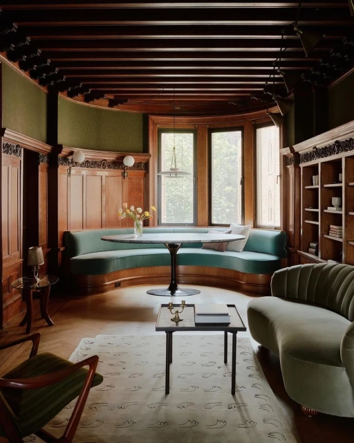 Interior of a room with a round table, cushioned seating, wooden accents, and a patterned rug, creating a stylish and inviting space.