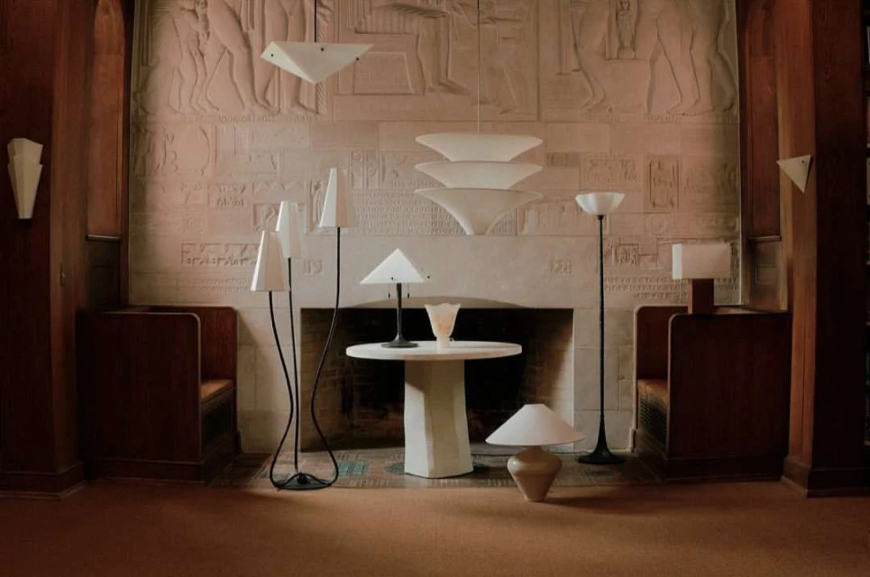 Interior room with a decorative fireplace, sculptural lamps, round table, and built-in wooden seating for a unique, artful space.