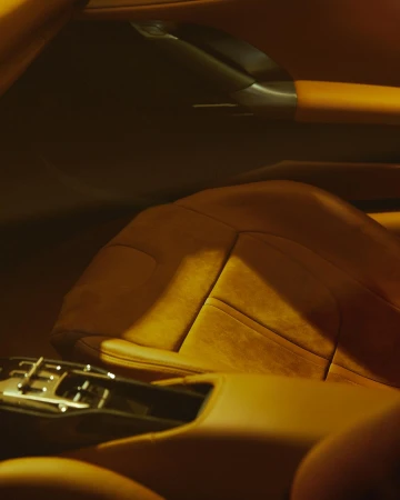 Close-up of car interior showing a leather car seat with a center console.  Warm, brown tones are used throughout the interior.