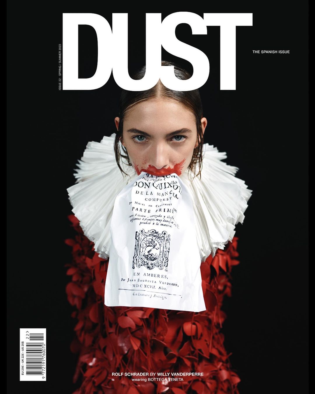 Magazine cover featuring a model with red makeup, a white ruffled collar, and a red floral dress against a stark black background.