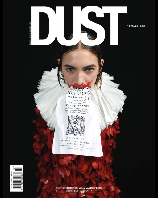 Magazine cover featuring a model with red makeup, a white ruffled collar, and a red floral dress against a stark black background.