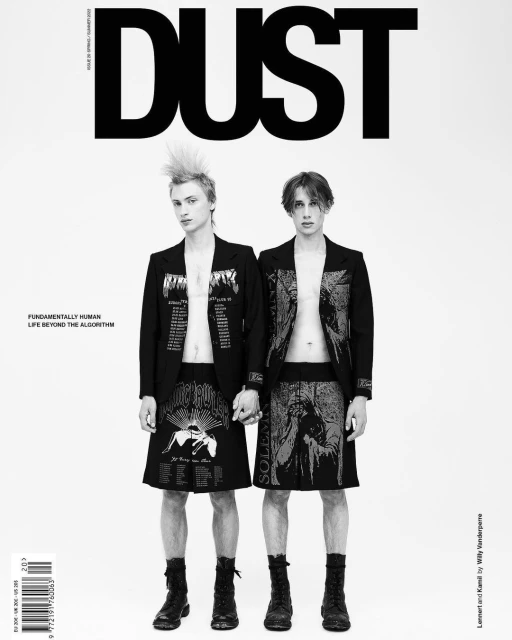 Black-and-white magazine cover of DUST featuring two male models in blazers and skirts, holding hands, against a bright white backdrop.