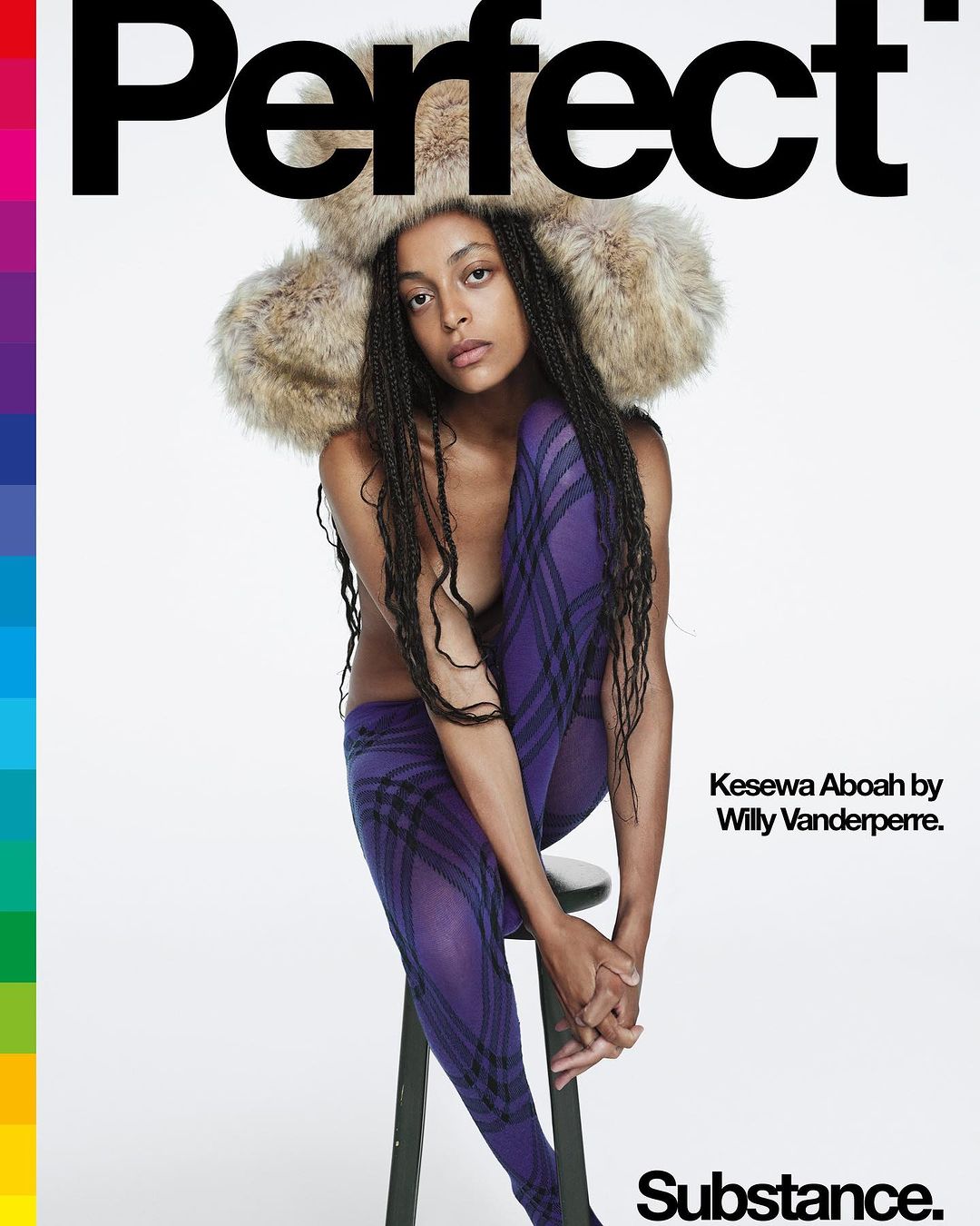 Editorial fashion shot of Kesewa Aboah in fur hat and purple plaid tights sitting on a stool against a bright white backdrop.