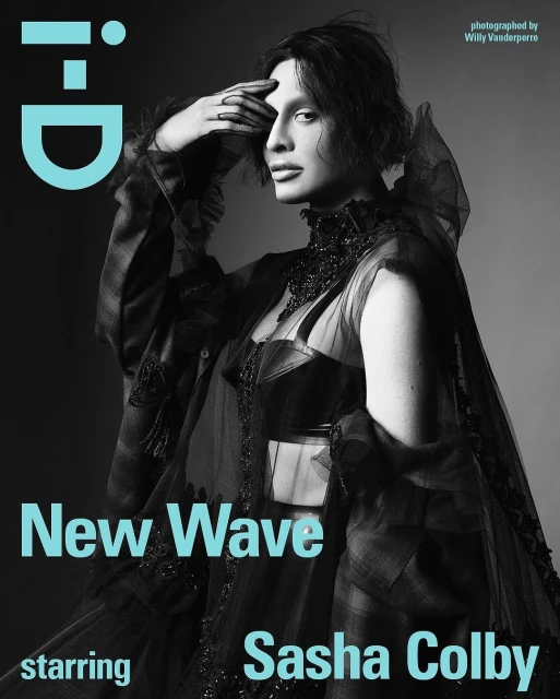 Sasha Colby poses in black clothing for an i-D Magazine cover; the image features a close-up portrait with a grey gradient background.