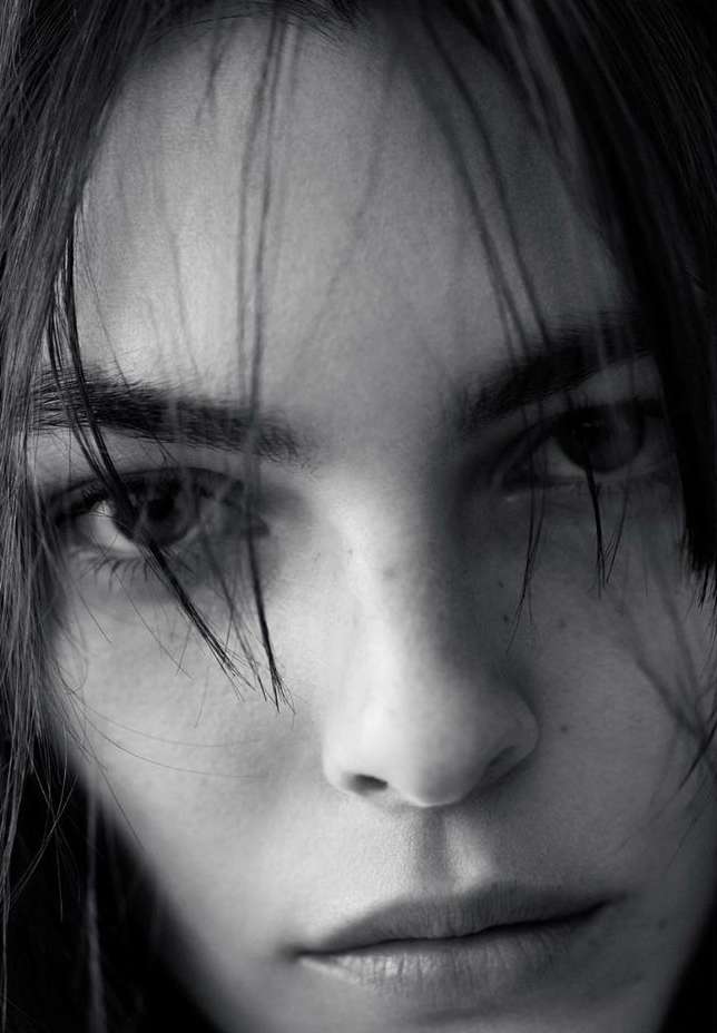 Close-up monochrome portrait of a person's face with stray strands of hair falling across the forehead.