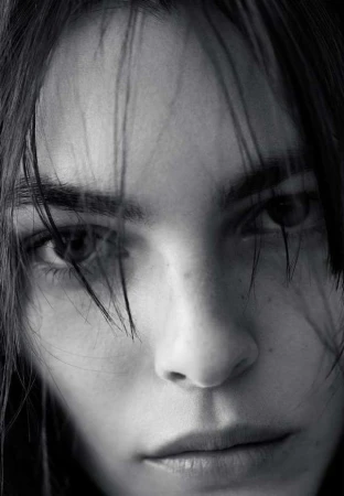 Close-up monochrome portrait of a person's face with stray strands of hair falling across the forehead.