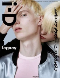 Close-up portrait of two models with blonde hair, featuring a silver bomber jacket and a pink t-shirt against a plain grey background.