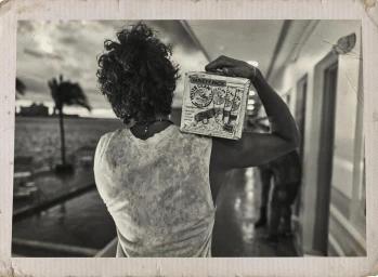 Black and white portrait of a man with curly hair carrying a White Claw box on his shoulder by Wolfgang Zac