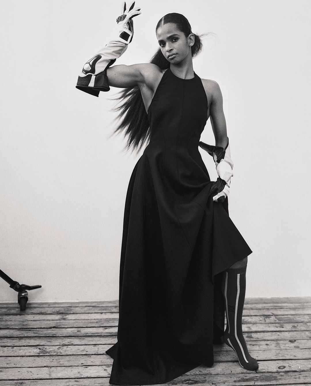 Model in long black dress wearing patterned arm guards and striped socks by Xavier Scott Marshall